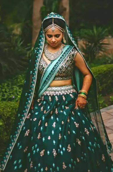 Photo of A bride in a dark green lehenga with a satlada for her wedding